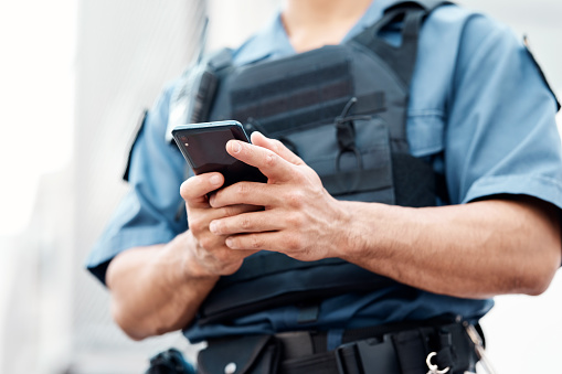 Man, police and hands with phone for networking, communication or social media in the city. Closeup of male person or officer typing, texting or chatting on mobile smartphone app in an urban town