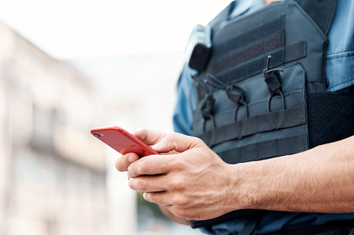 Man, police and hands with phone for communication, networking or social media in the city. Closeup of male person or officer typing, texting or chatting on mobile smartphone app in an urban town