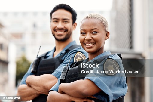 istock Happy police, team and arms crossed in confidence for city protection, law enforcement or crime. Portrait of man and woman officer standing ready for justice, security or teamwork in an urban town 1575561898