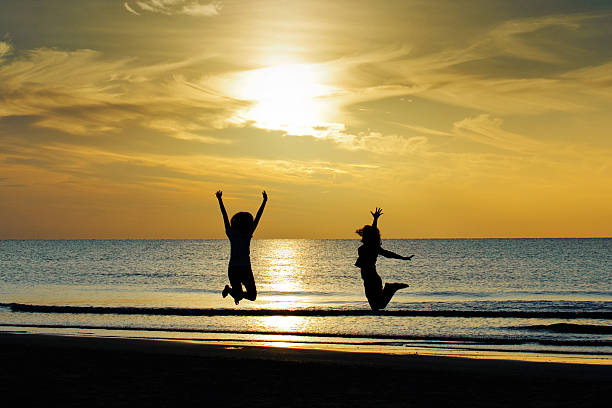 Girls jumping on the beach stock photo