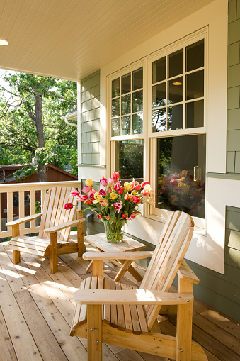 Two adirondack chairs and tulips on a homes' front porch.