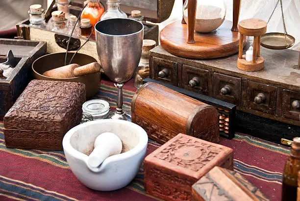 Lot of ancient alchemist instruments, boxes and bottles over a table