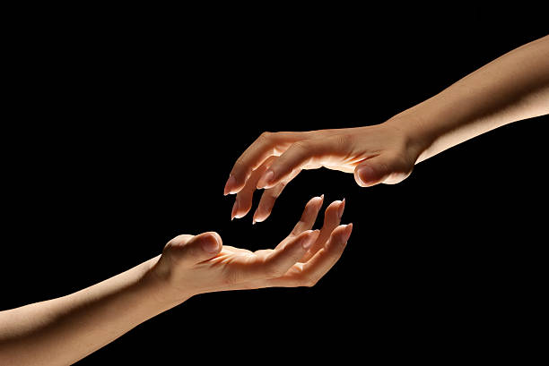 istock Two Hands Reach Out In Darkness to Hold One Another 157558206