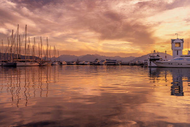Sailboats moored on harbor. Scenic view of sea against cloudy sky. Beautiful view of nature during sunset.