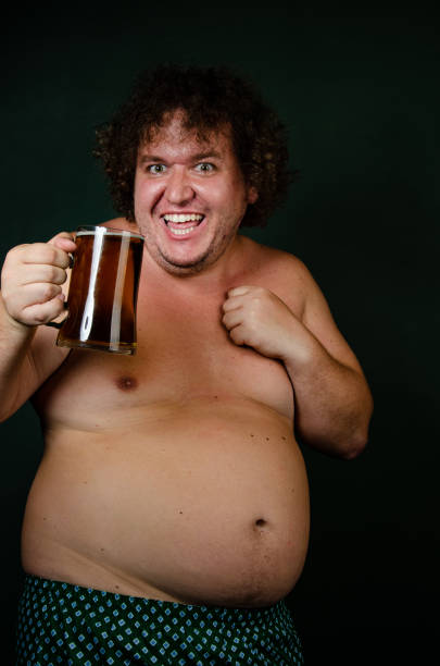istock Funny fat man drinks beer on an Irish holiday. 1575586680