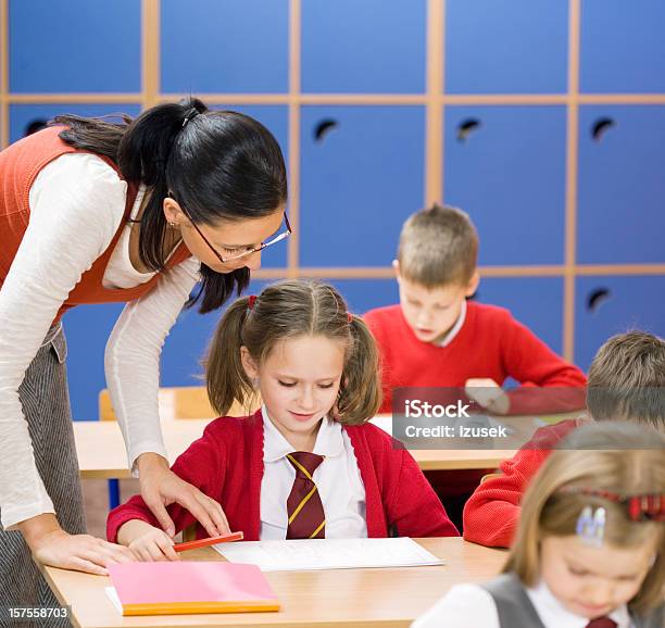 Elementary School Children Teacher Helping Stock Photo - Download Image Now - 6-7 Years, Adult, Bending