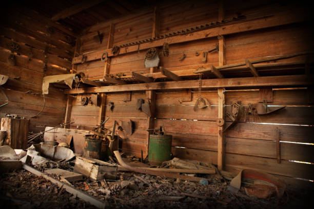 Grungy, color photo of an old, abandoned barn room with antique gears, barrels and other trash. Compiled from three exposures. Slight grain added for grungy feel.