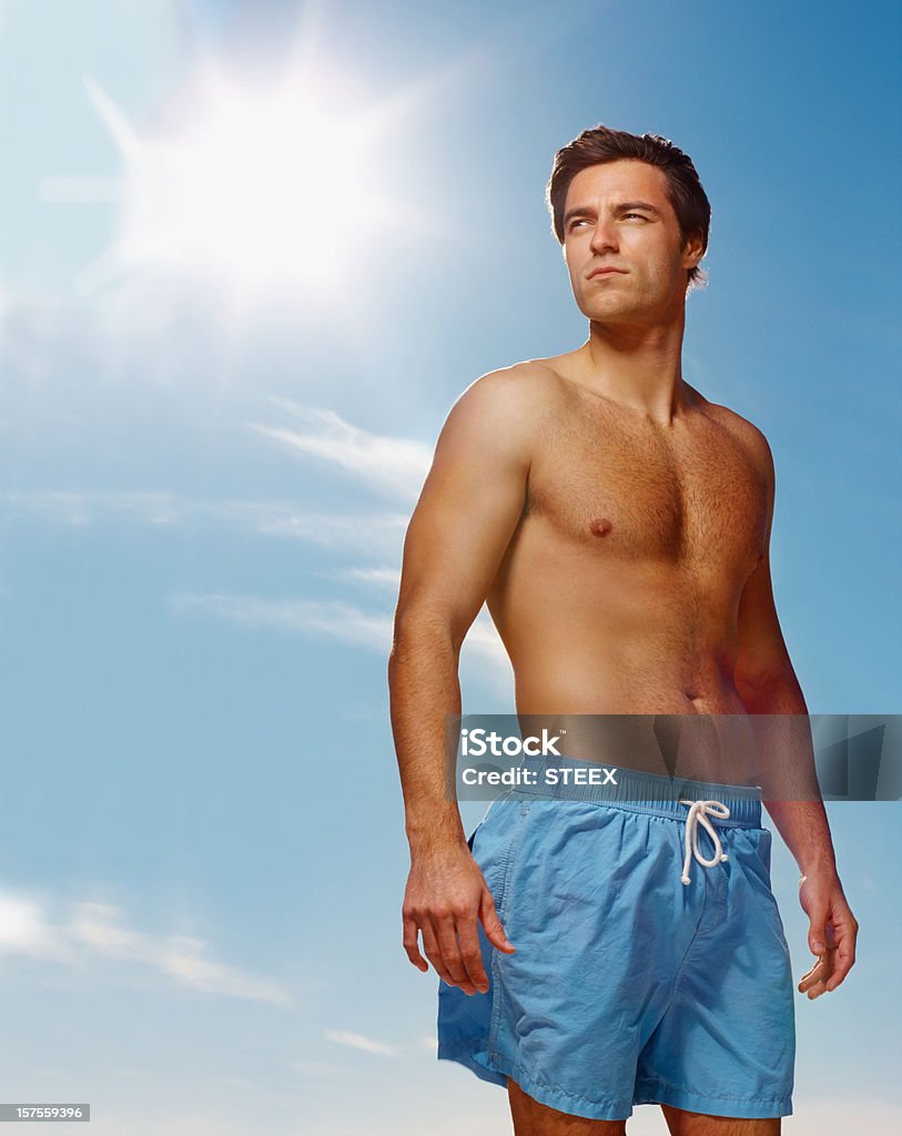Torse nu jeune homme seul debout contre le ciel bleu - Photo de 25-29 ans libre de droits