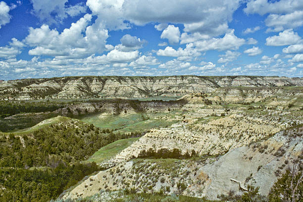 Cloud Formation Over a Badland Canyon Theodore Roosevelt National Park lies where the Great Plains meet the rugged Badlands near Medora, North Dakota, USA. The park's 3 units, linked by the Little Missouri River is a habitat for bison, elk and prairie dogs. The park's namesake, President Teddy Roosevelt once lived in the Maltese Cross Cabin which is now part of the park. This picture of a classic badland formation was taken from the Scenic Loop Drive. jeff goulden badlands stock pictures, royalty-free photos & images