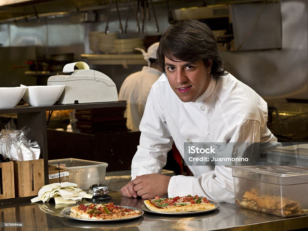 Restaurant Owner Hispanic cook posing with two slices of pizza at a restaurant counter  (this picture has been taken with a Hasselblad H3D II 31 megapixels camera) Pizzeria Stock Photo