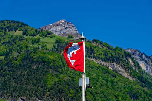 Passenger ship named Weggis on Lake Lucerne with waving flag on a sunny spring day. Photo taken May 22nd, 2023, Flüelen, Switzerland.