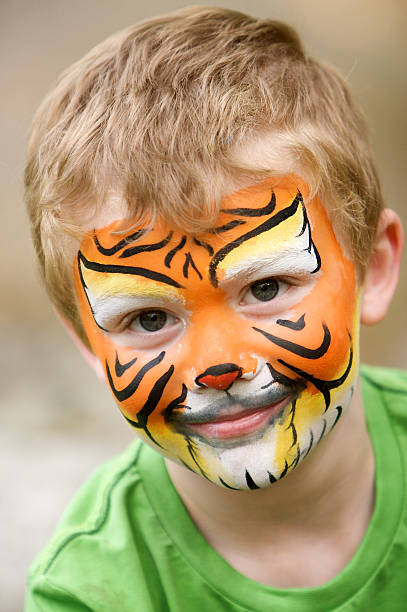 Young boy in green shirt with tiger face paint stock photo