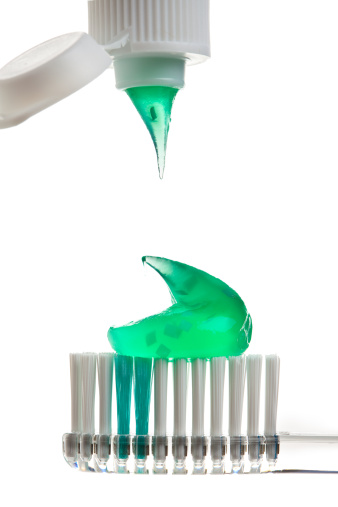 A macro of a toothbrush and tooth paste on a white background