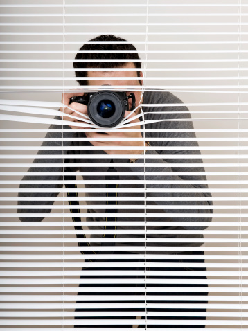 Men taking pictures with camera behind blinds.