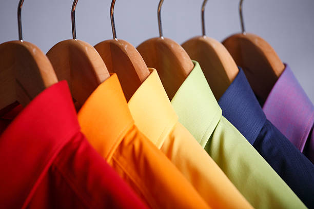 Close-up of rainbow shirt collars hanging in closet Rainbow colored shirts on hangers. dry cleaner stock pictures, royalty-free photos & images