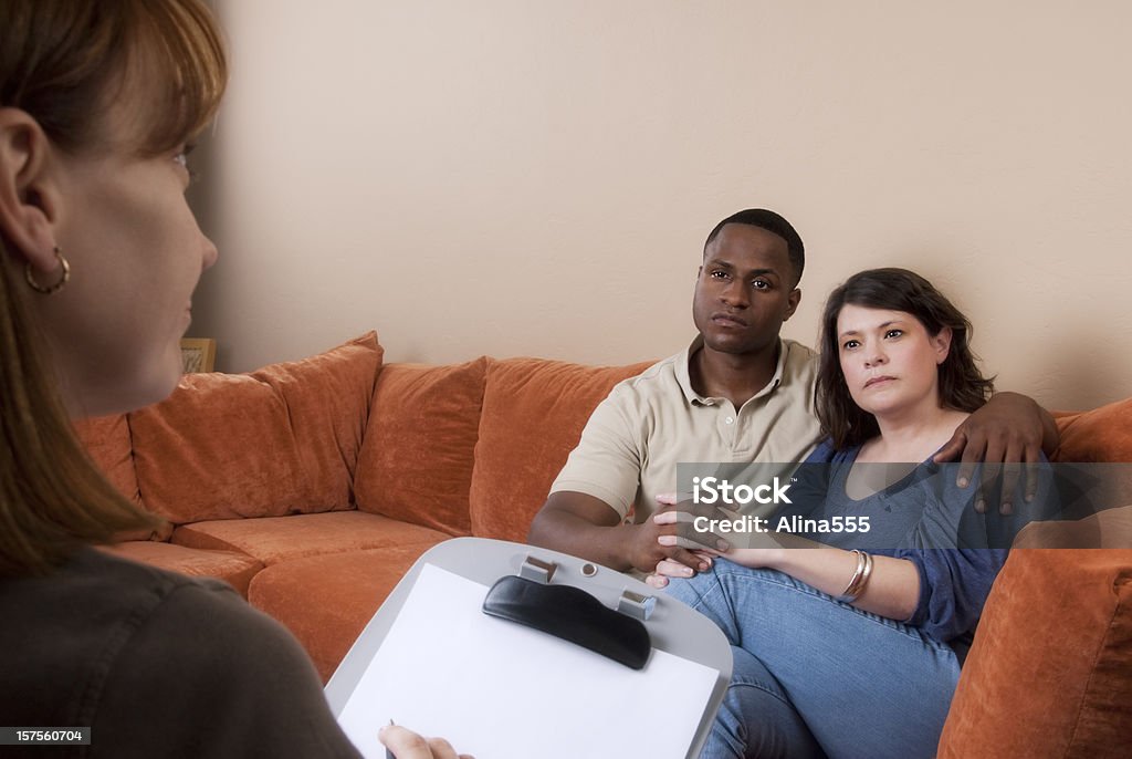 Bi-raza mestiza en el sofá mirando a un médico o terapia - Foto de stock de Grupo multiétnico libre de derechos