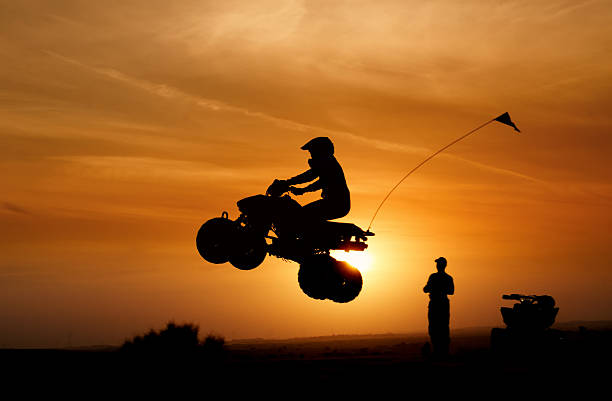 bicicleta de quatro lugares pulando ao pôr-do-sol - off road vehicle quadbike motocross desert - fotografias e filmes do acervo