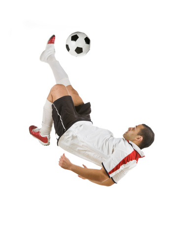 Soccer player doing a bicycle kick mid-air, isolated on white background.