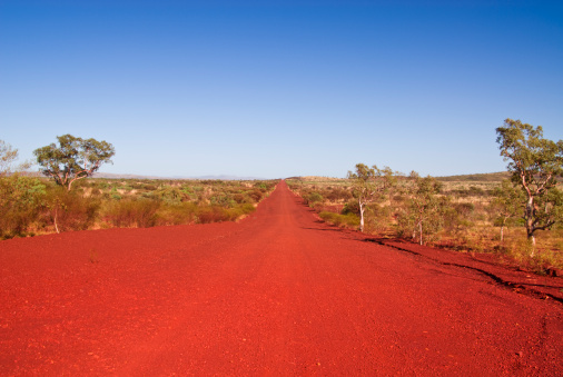 A long straight track (road) in Karijini National Park, Western Australia. Australians also call it dirt road.