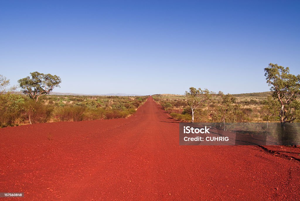 A shot of the outback track in the daytime A long straight track (road) in Karijini National Park, Western Australia. Australians also call it dirt road. Outback Stock Photo
