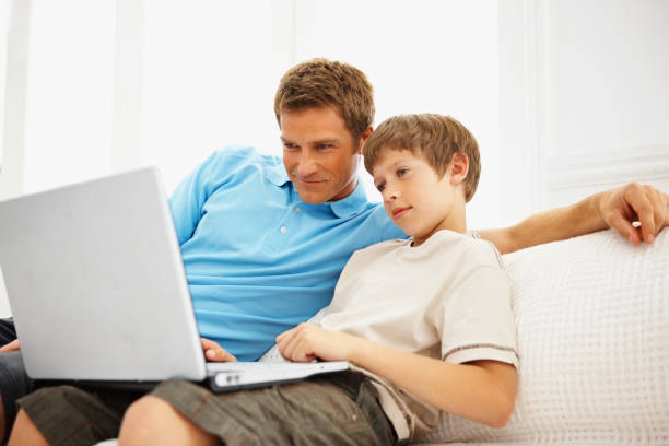 istock Father and son using a laptop together while at home 157560854