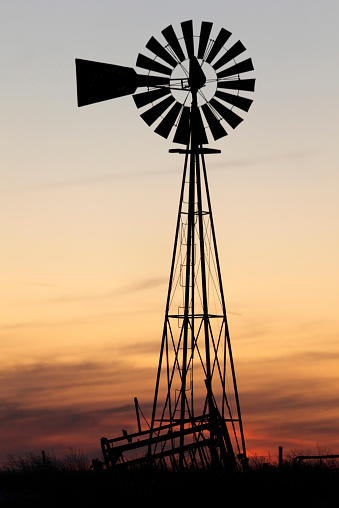 Sunset over the western kansas prairie with windmill silouette in foreground.  Portrait orientation.
