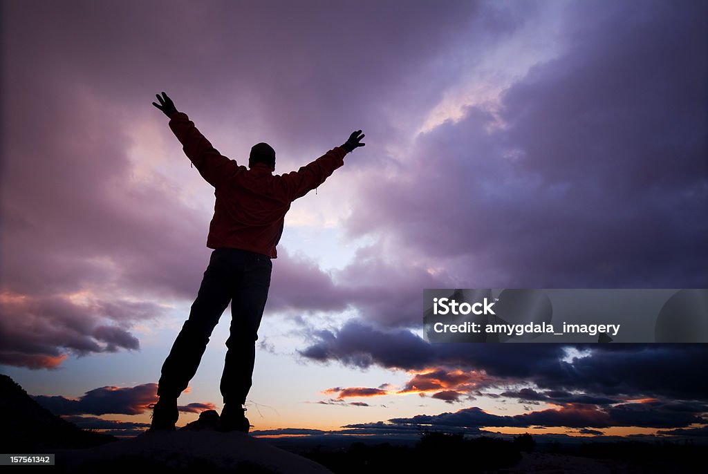 silhouette uomo con le braccia sollevate al tramonto nuvole di cielo - Foto stock royalty-free di Braccia tese