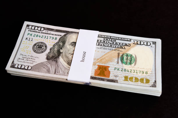 istock A stack of dollars with the inscription house on a dark background. 1575621054