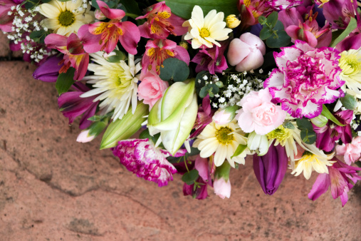 Mixed flower funeral wreath on pink stone.