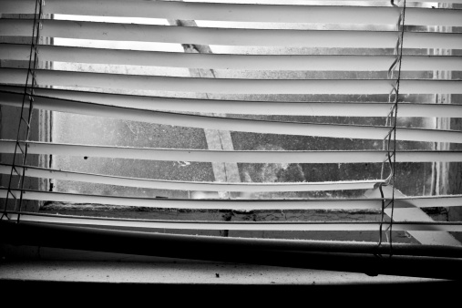 Landscape view of an old window (and frame) with dusty window shades.