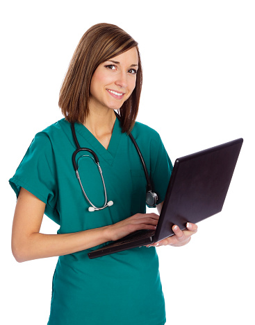 A smiling young woman wearing scrubs holding a laptop computer.