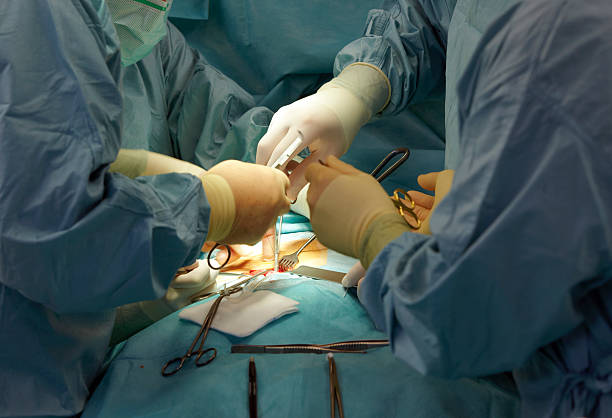 Doctors in scrubs operating on a patient using instruments stock photo