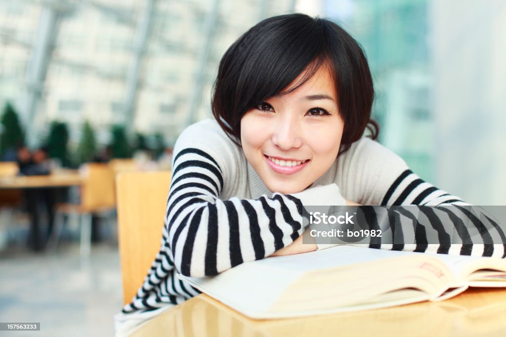 young female student put head on book young female student put head on book , looking at camera 20-24 Years Stock Photo