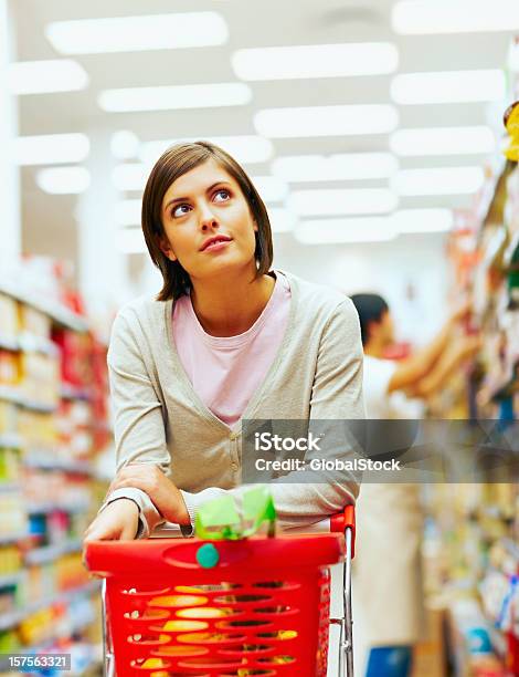 Jovem Mulher Com Um Vermelho Carrinho De Compras No Supermercado - Fotografias de stock e mais imagens de Supermercado