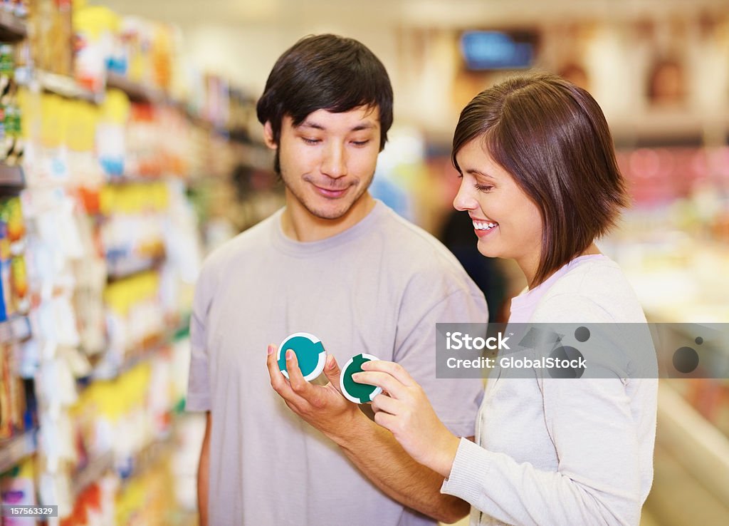 Casal decidir em um produto para compra no supermercado - Foto de stock de 20-24 Anos royalty-free