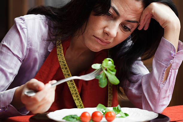 istock A woman making a frown face at salad on her fork 157563716