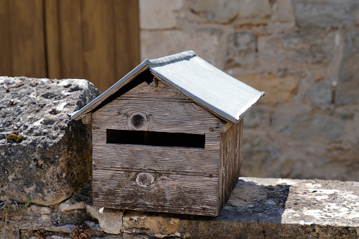 wooden dark grey classic letter box natural on old ancient stone wall fence outdoors street