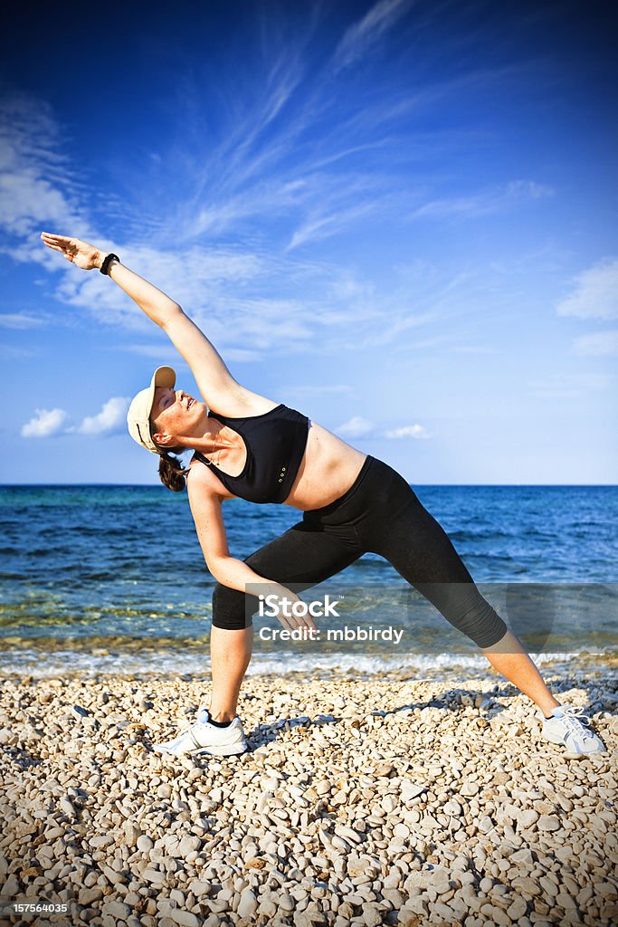 Adulto joven mujer haciendo ejercicio de yoga en la playa en la mañana - Foto de stock de Actividad libre de derechos