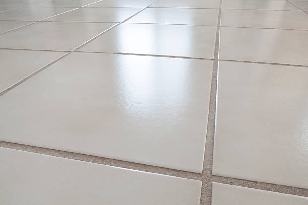 Unrecognizable male Caucasian worker lying down ceramic tiles in a room.