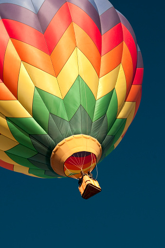 A brightly colored hot air balloon sailing through a clear blue sky.