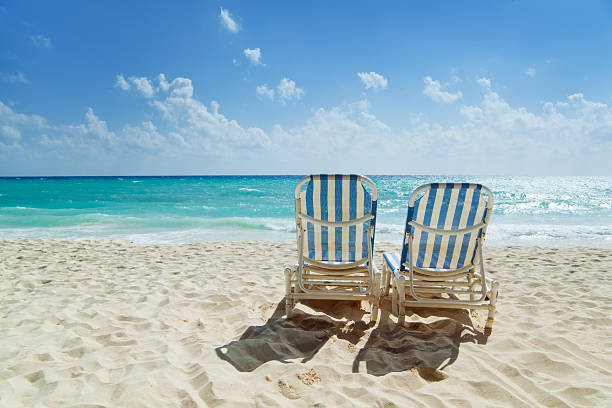 Subject: Two beach chairs on a sandy beach along the Caribbean Sea.