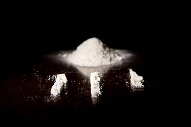 Three lines of cocaine next to a pile of it White powder looking like cocain on dark brown empty Kitchen table with three lines cocaine photos stock pictures, royalty-free photos & images