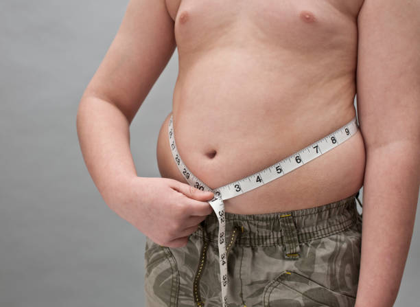 istock Overweight Boy with tape measure around belly 157564651