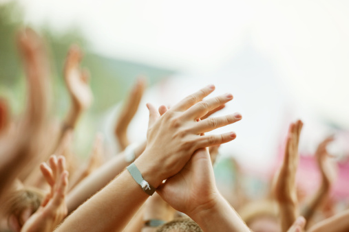 Large party group of people holding their arms and hands high in the air during an Outdoor Concert