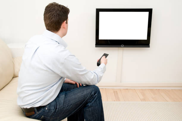 istock Man uses remote control to change channel on flatscreen tv 157565275