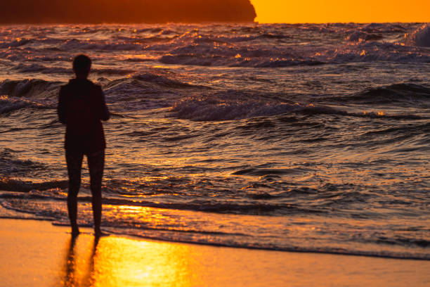 Photo of Unrecognized human watched stormy waves on Baltic Sea. Golden hour.