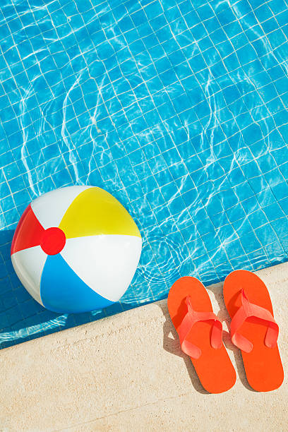 プールに浮かぶ楽しい夏のビーチボール、ビーチサンダル - playing the ball ストックフォトと画像