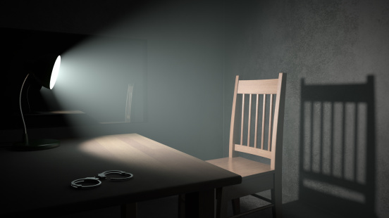 A spotlight pointing at an empty chair in a dark interrogation room. Very detailed high resolution 3D render.