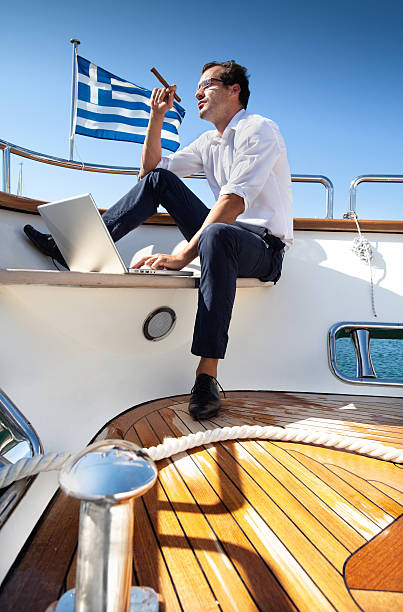 Businessman on yacht smoking a cigar while using laptop