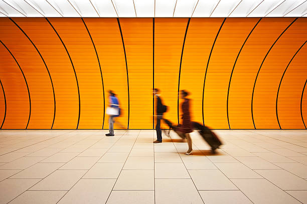 Blurred people walking with luggage in an orange tunnel stock photo